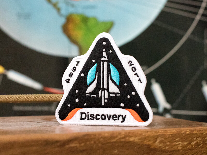 Discovery embroidered patch on a desk in front of a globe