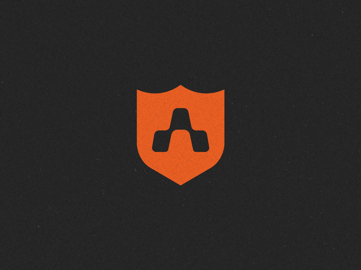 The Hall of Game shield mark: an orange football-style shield with a geometric A cut out of it, on textured charcoal