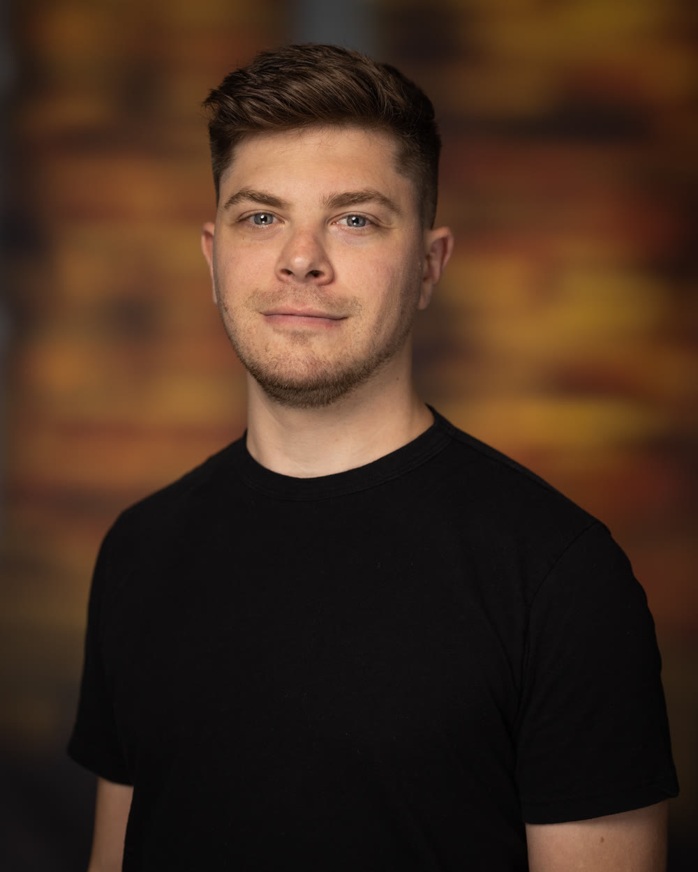 Portrait of Austin Remer in a black T-shirt against a warm, blurred background